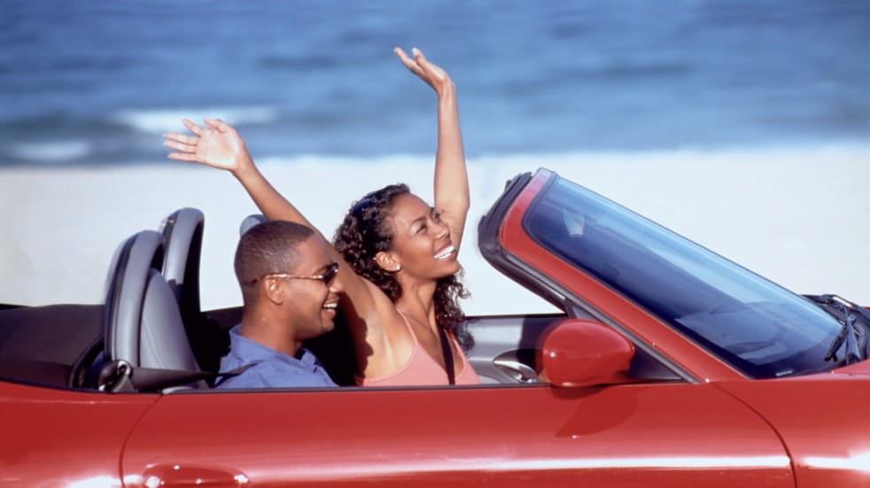 Should you buy a convertible car couple driving convertible car along beach